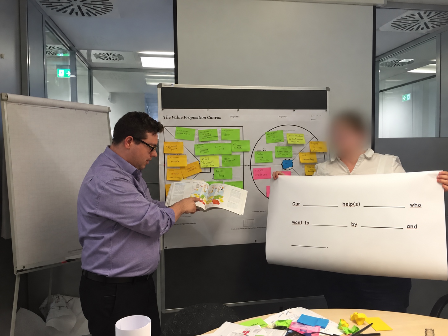 Teilnehmer besprechen ein ausgefülltes Value Proposition Canvas und eine Vorlage für Nutzenhypothesen